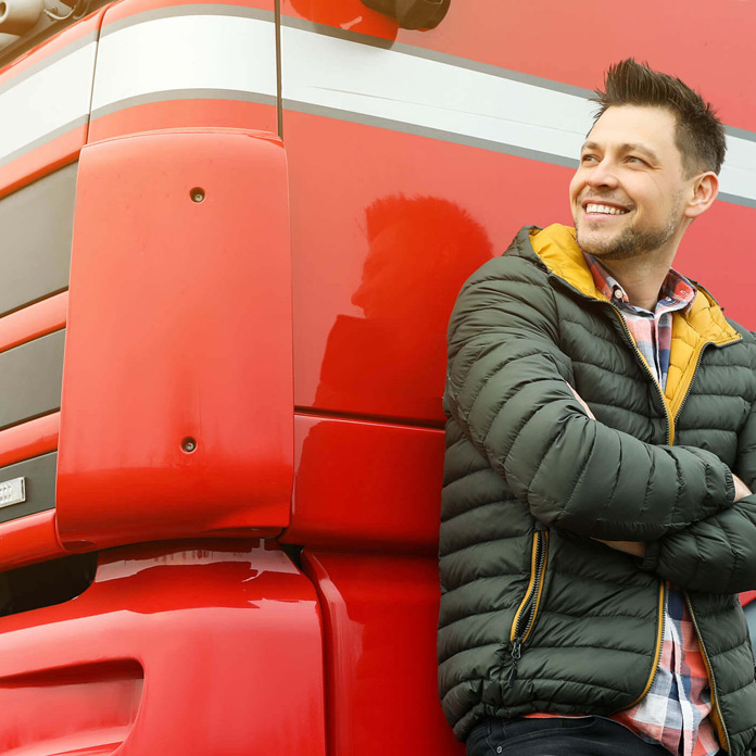A man leaning against the cab of his red truck