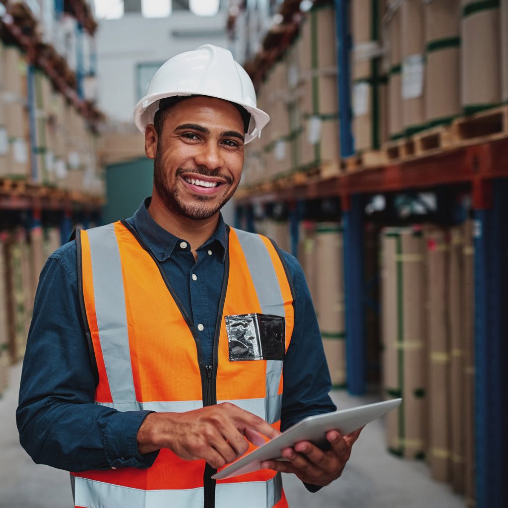 A warehouse manager smiling while working on their tablet